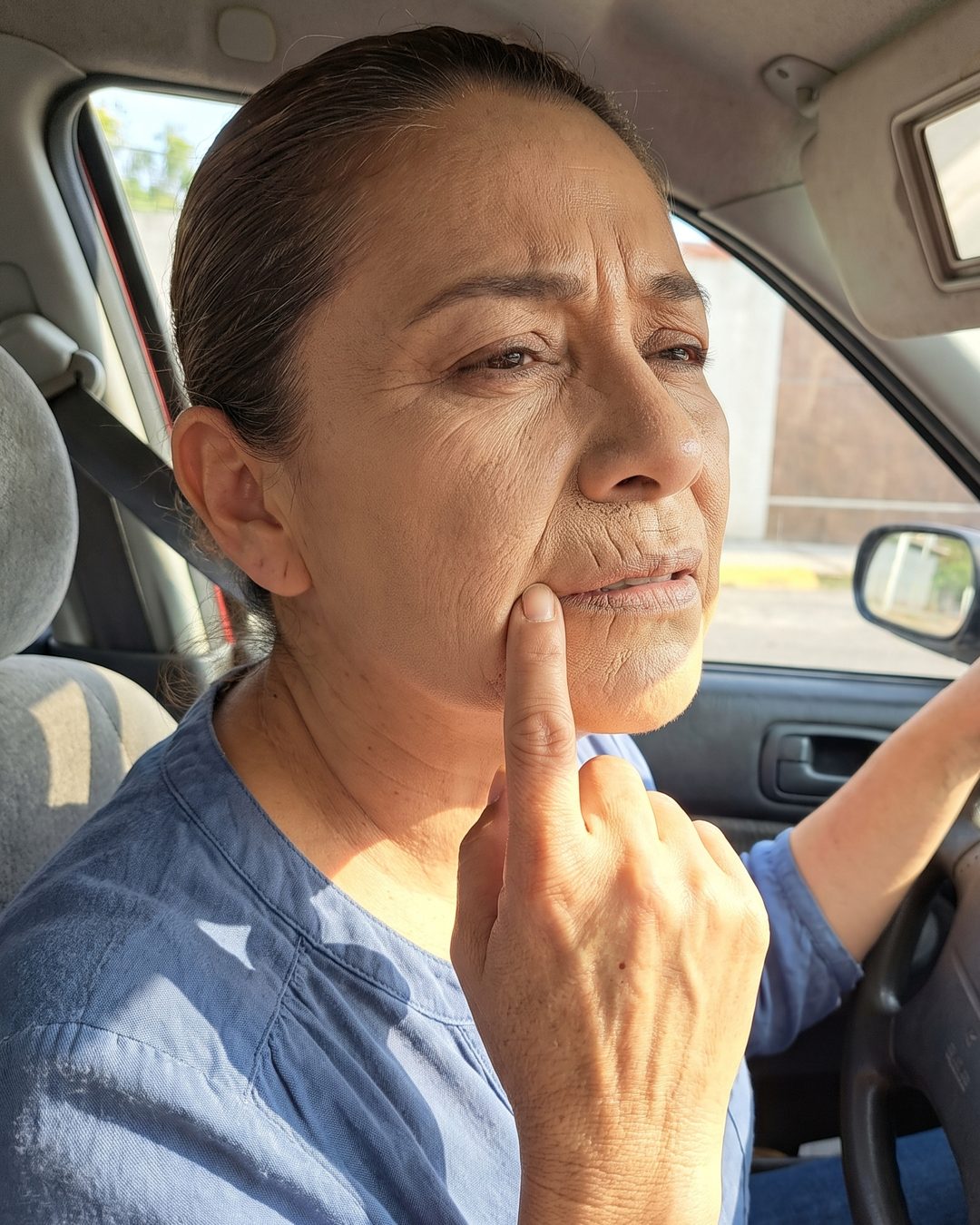 Mujer mirándose en el retrovisor del carro por la tarde